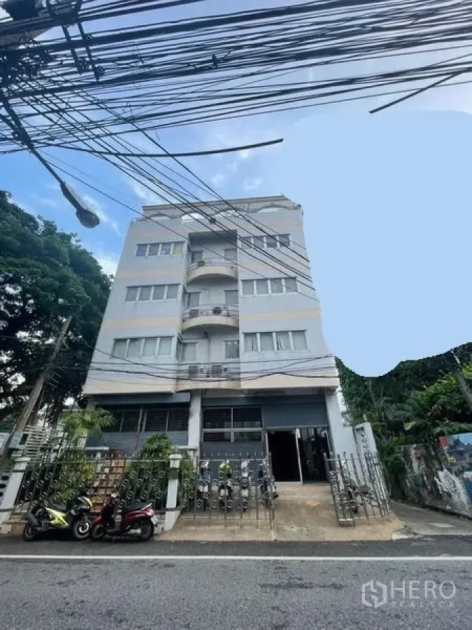 Home Office for sale in Yan Nawa, Bangkok - Street view of the building facade with balconies, gate, and parking area.