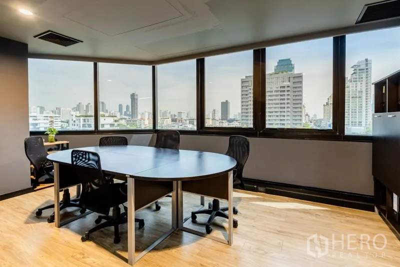 Office Space for rent - Meeting room with round table, mesh chairs and wraparound windows.