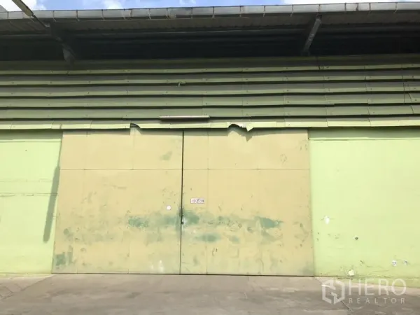 货栈 出租在Khlong Toei, Bangkok - 仓库外墙上的大型金属装卸双扇门与加长屋檐。