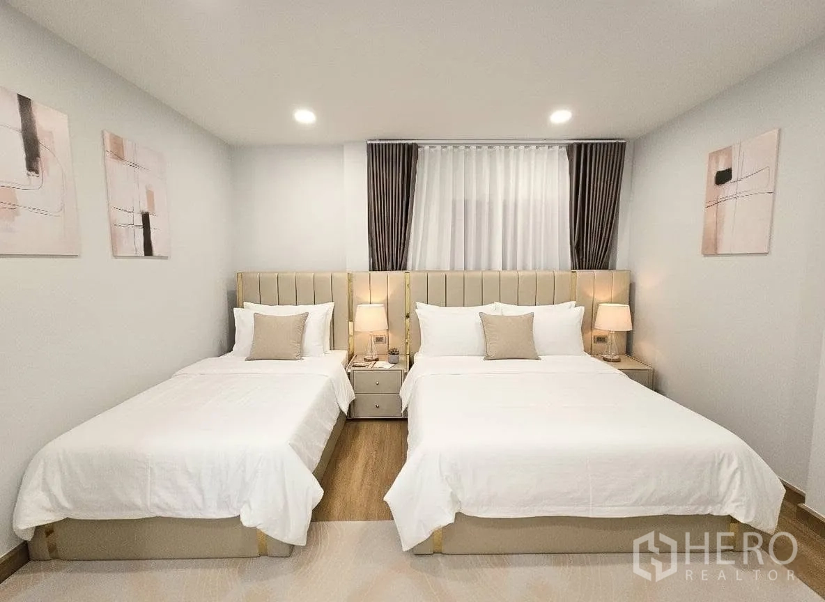 Detached House for rent or sale in Bang Phli, Samut Prakan - Front view of twin‑bed bedroom with upholstered headboards, nightstands and soft drapes.