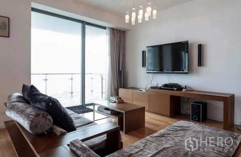 คอนโด ให้เช่าหรือขายในYan Nawa, Bangkok - ห้องนั่งเล่น ทีวีติดผนัง โคมแขวน และประตูกระจกเปิดออกสู่ระเบียง