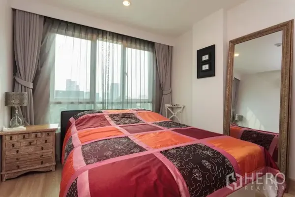 公寓 出租在Khlong Toei, Bangkok - 卧室采光好，落地窗、彩色被套、床头柜与全身镜。