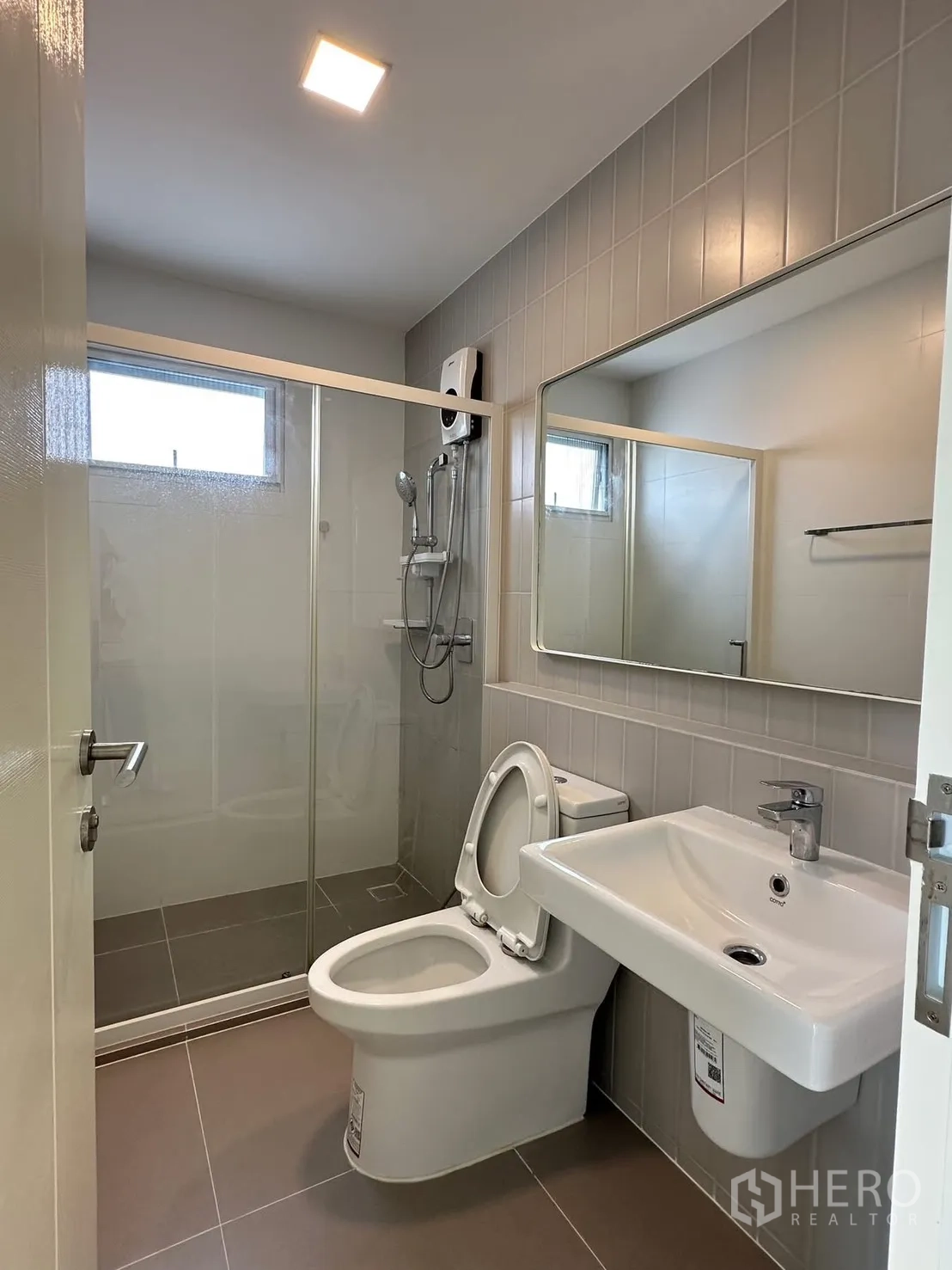 联排别墅 for rent in Prawet, Bangkok - 卫生间带玻璃淋浴房、坐便器、长镜与热水器。