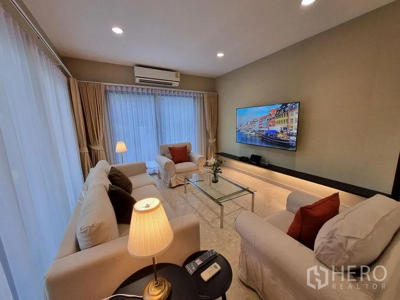 Detached House for rent in Bang Khae, Bangkok - Another angle of the living room with floor-to-ceiling curtains, lamps, and a large TV.