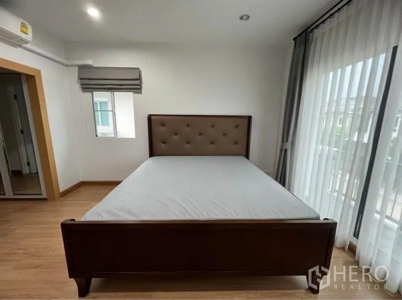 独立式住宅 出租在Suan Luang, Bangkok - 主卧，软包床与通向阳台的落地门