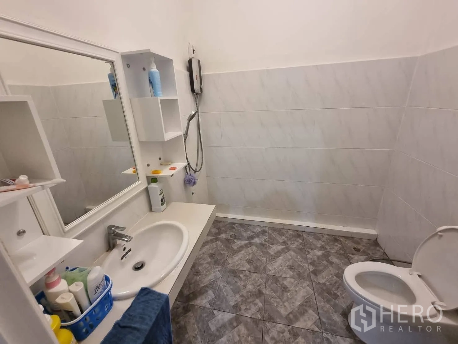 Townhouse for rent in Din Daeng, Bangkok - Bright bathroom with wall-mounted vanity, mirror, shower and toilet on gray tile floor.