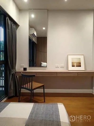 Townhouse for rent in Watthana, Bangkok - Bedroom corner with built-in dressing table, mirror, and chair by window.