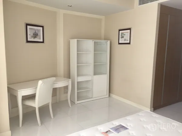 คอนโด ให้เช่าในKhlong Toei, Bangkok - มุมห้องนอนมีโต๊ะทำงานสีขาว เก้าอี้บุนวม และตู้หนังสือบานกระจก โทนสีอบอุ่น