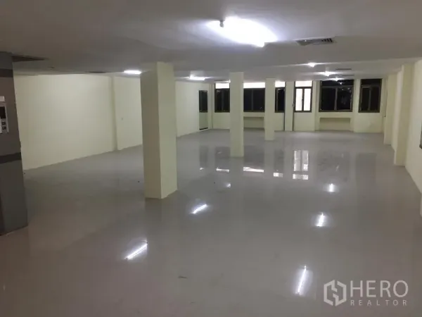 Home Office for rent in Watthana, Bangkok - Expansive empty office floor with support columns, windows on two sides and polished tiles.