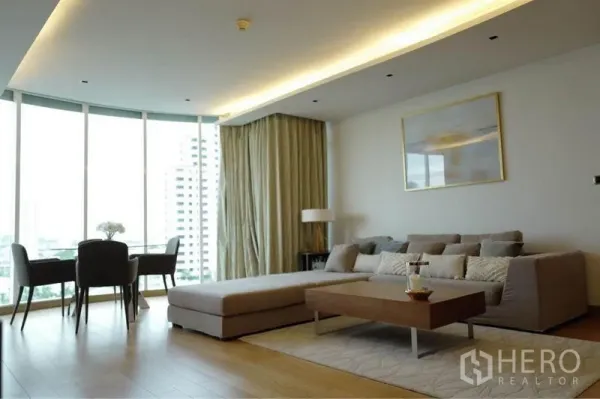 คอนโด ให้เช่าหรือขายในPhaya Thai, Bangkok - ห้องนั่งเล่นรับแสงธรรมชาติ โซฟาเข้ามุม โต๊ะกลาง และผนังกระจกโค้งพาโนรามา