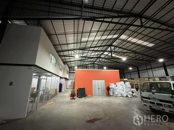 货栈 出租 - 高挑钢结构屋顶的宽敞仓库，中央装卸区与橙色隔间。