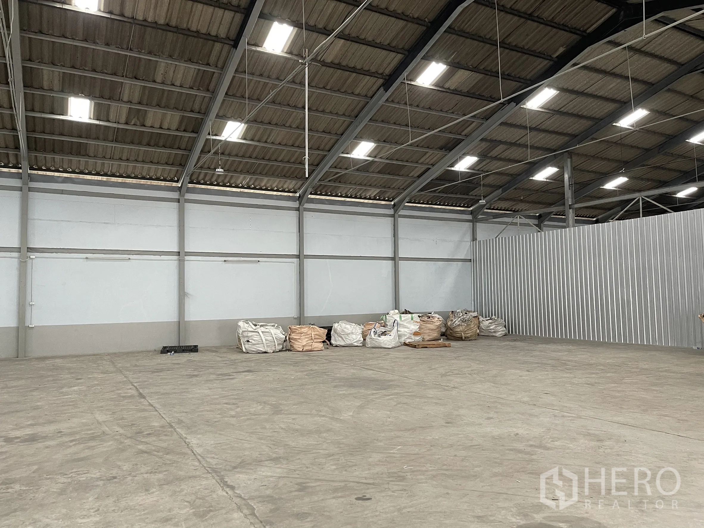 โรงงาน for rent in Mueang Samut Prakan, Samut Prakan - มุมโรงงานที่มีผนังกั้นเมทัลชีทและกระสอบวัสดุตั้งเรียง