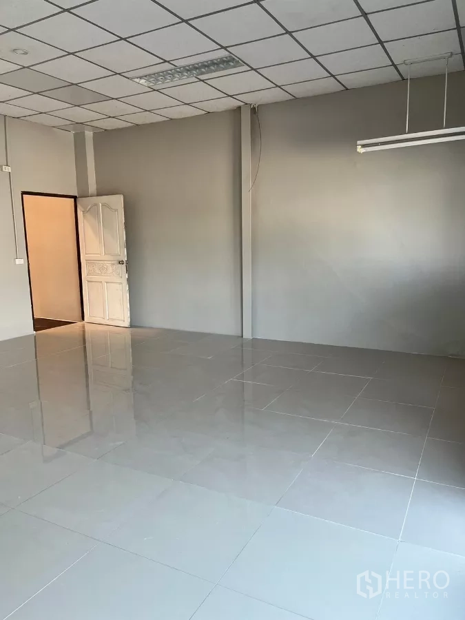 Warehouse for rent in Lat Lum Kaeo, Pathum Thani - Glossy tiled office room with gray walls and fluorescent lighting.