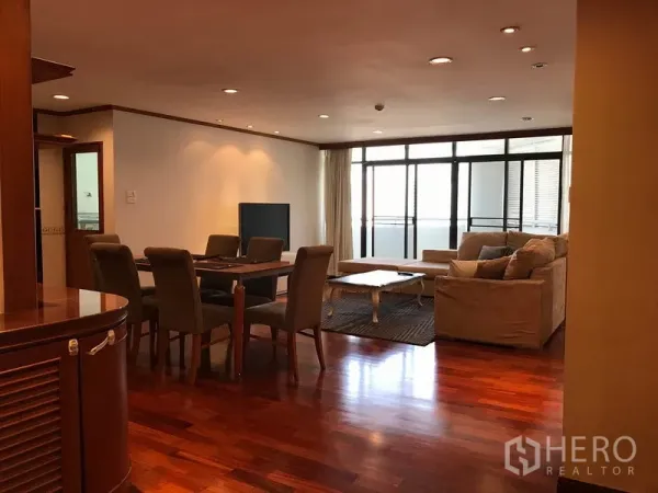 Condominium for rent in Watthana, Bangkok - Spacious living and dining area with hardwood floors and floor-to-ceiling windows leading to a balcony.