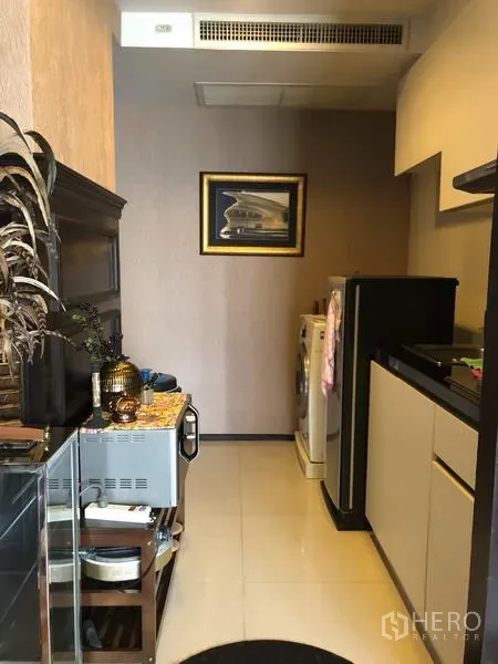Condominium for rent in Pathum Wan, Bangkok - Compact kitchenette with cabinets, refrigerator and in-unit washing machine.