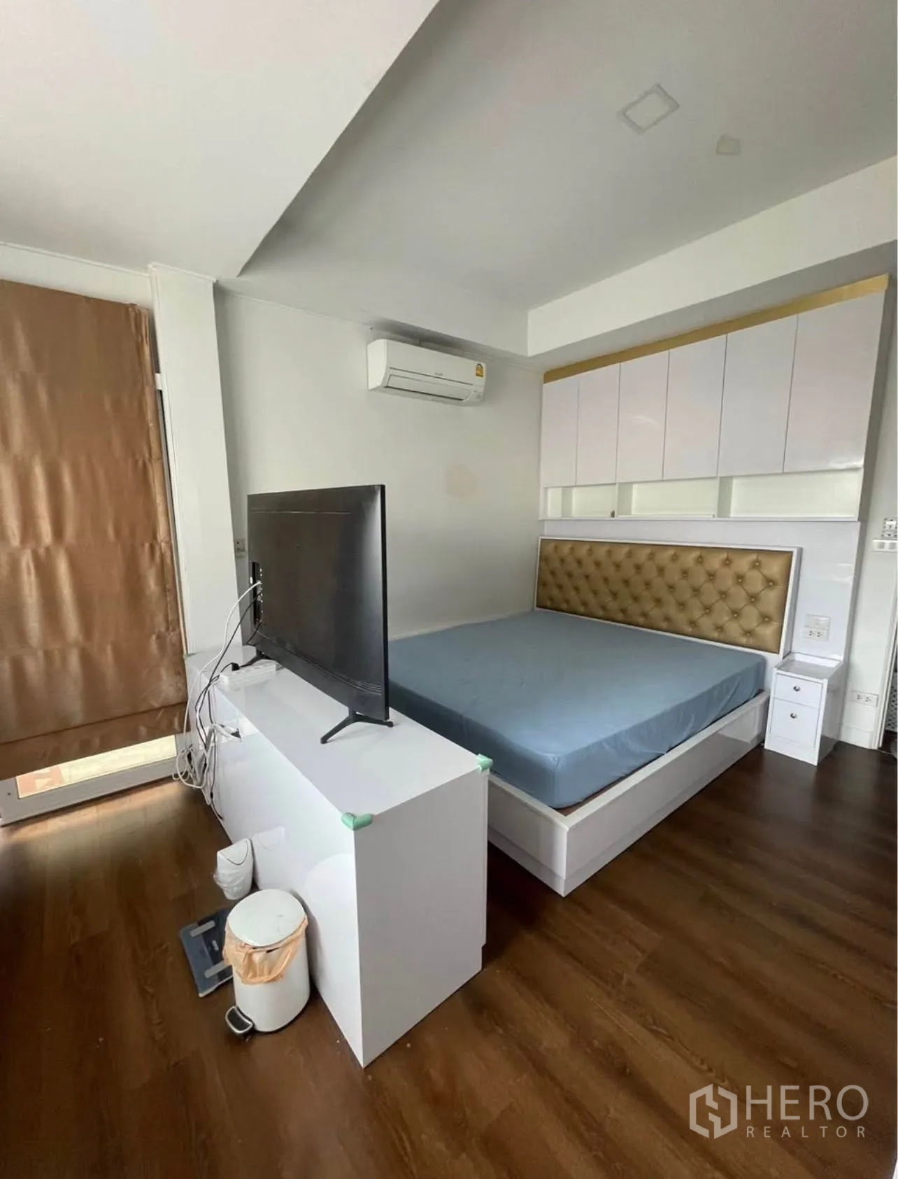 Detached House for rent or sale in Lam Luk Ka, Pathum Thani - Bedroom with wood flooring, bed, TV on console, air conditioner, and built-in cabinets.