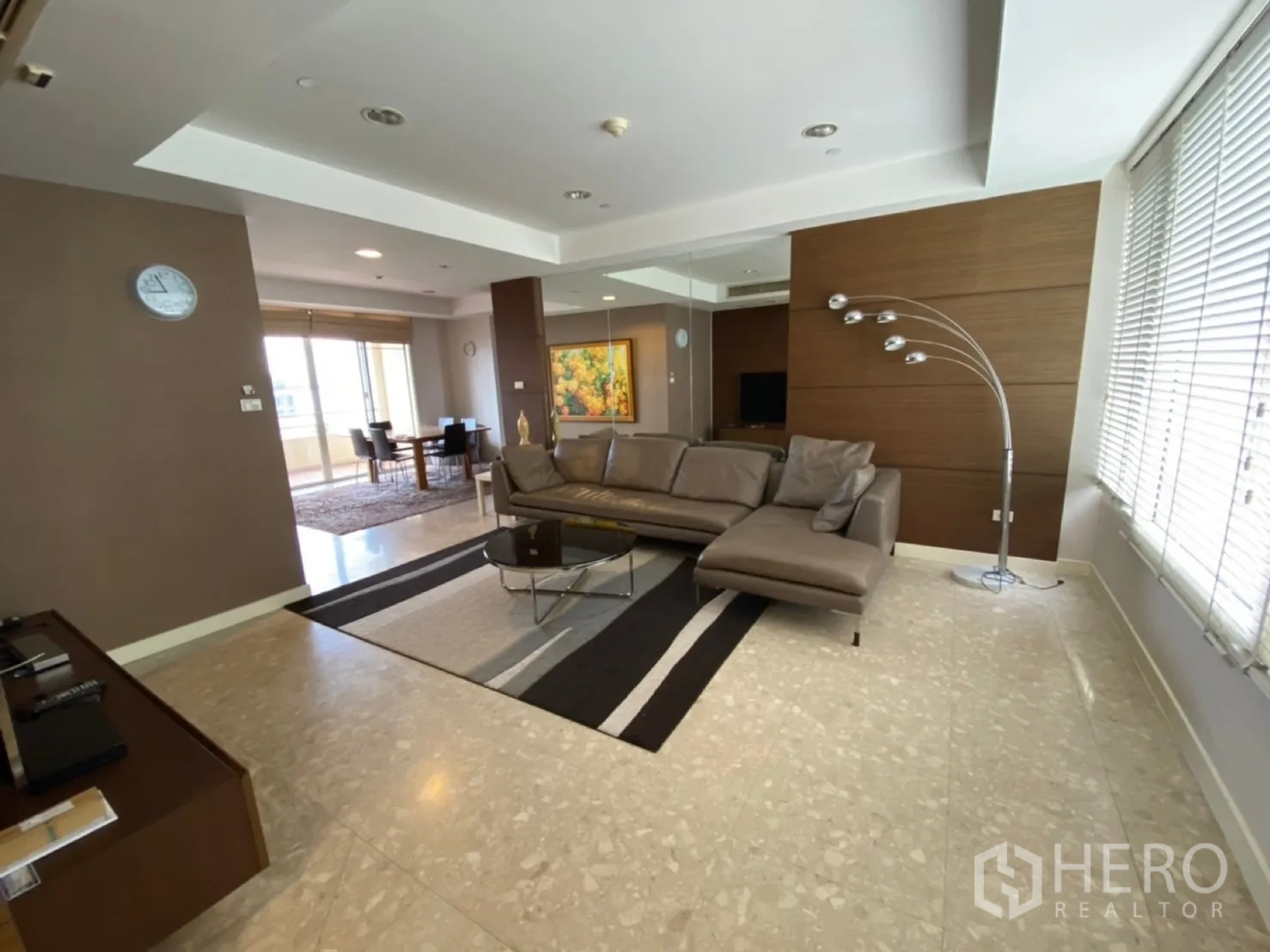 Condominium for rent in Watthana, Bangkok - Bright living room with L-shaped leather sofa, floor lamp and large windows.