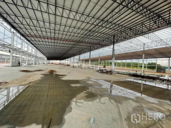 คลังสินค้า ให้เช่าในPluak Daeng, Rayong - ทัศนียภาพภายในลึกยาว พื้นมีน้ำขังบางส่วน มองเห็นพื้นที่สีเขียวด้านนอก