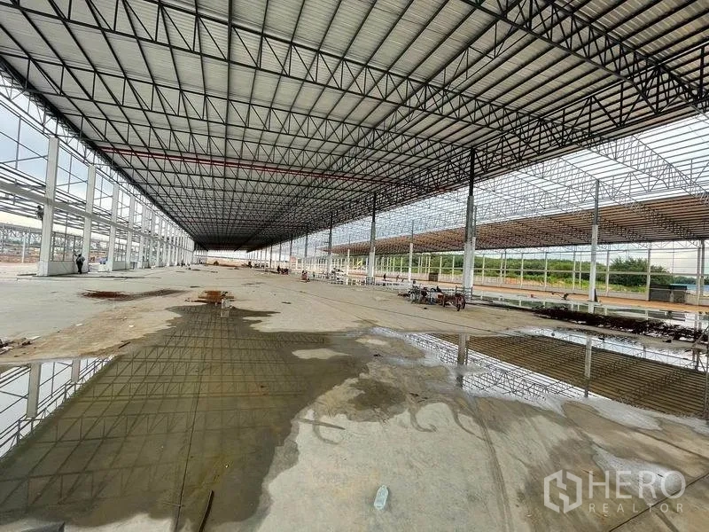 คลังสินค้า ให้เช่าในPluak Daeng, Rayong - ทัศนียภาพภายในลึกยาว พื้นมีน้ำขังบางส่วน มองเห็นพื้นที่สีเขียวด้านนอก