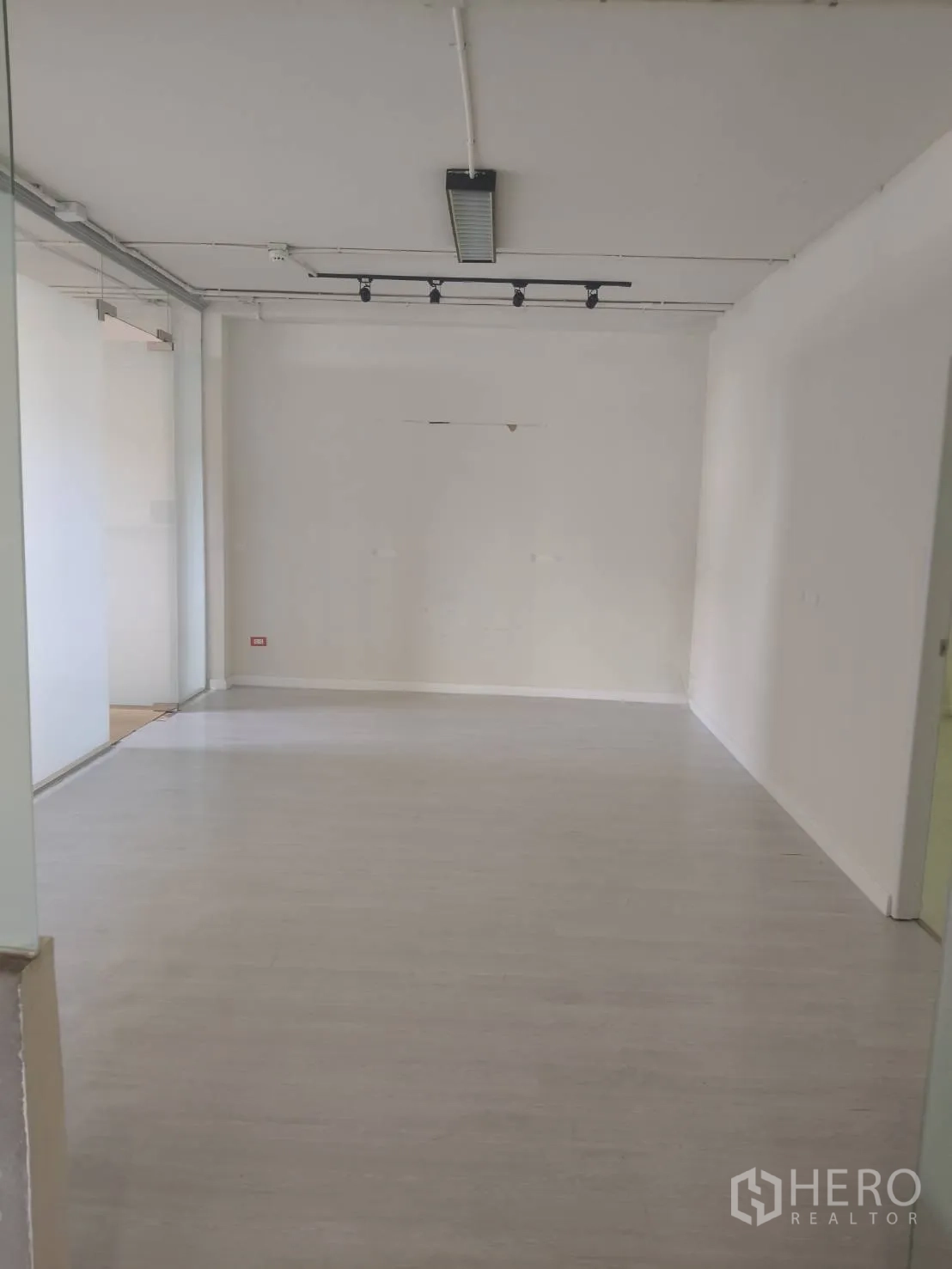 Office Space for rent in Khlong Toei, Bangkok - Clean white-box office area with light wood flooring, a glass partition and ceiling track lighting.