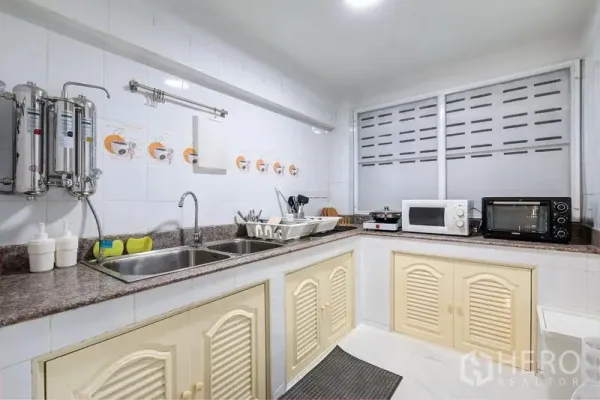 Townhouse for rent in Bang Rak, Bangkok - White tiled kitchen with double sink, stone countertops, and small appliances.