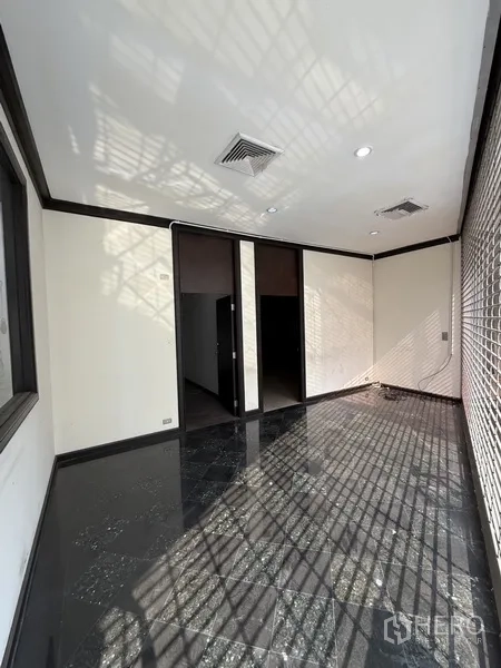 零售空间 出租在Sathon, Bangkok - 小型房间，深色亮面地坪、白墙与窗户安全栅。