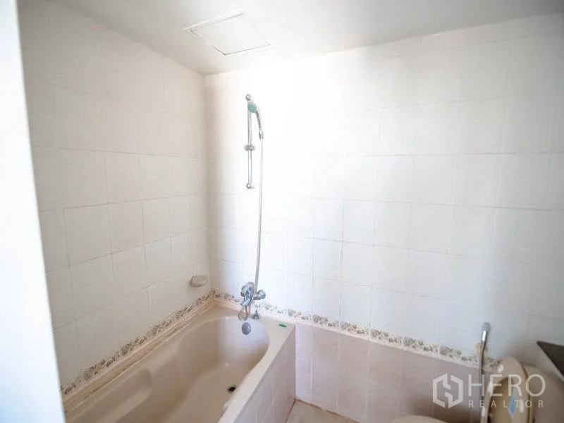 Condominium for rent in Watthana, Bangkok - Bathroom with bathtub, handheld shower, and white tiled walls.