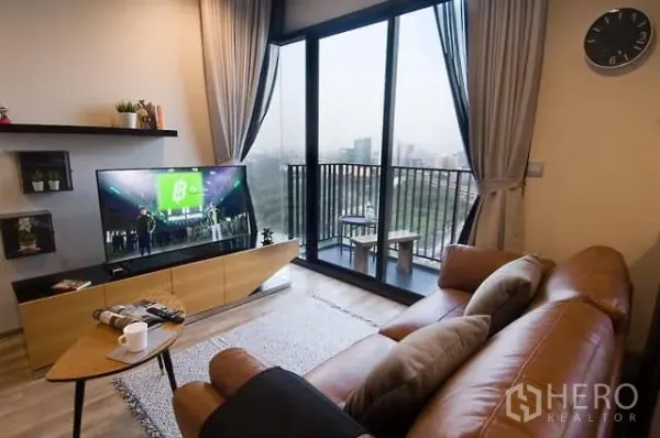 公寓 出租或出售在Chatuchak, Bangkok - 客厅配皮沙发与电视，落地门通向阳台，享公园与城市景观