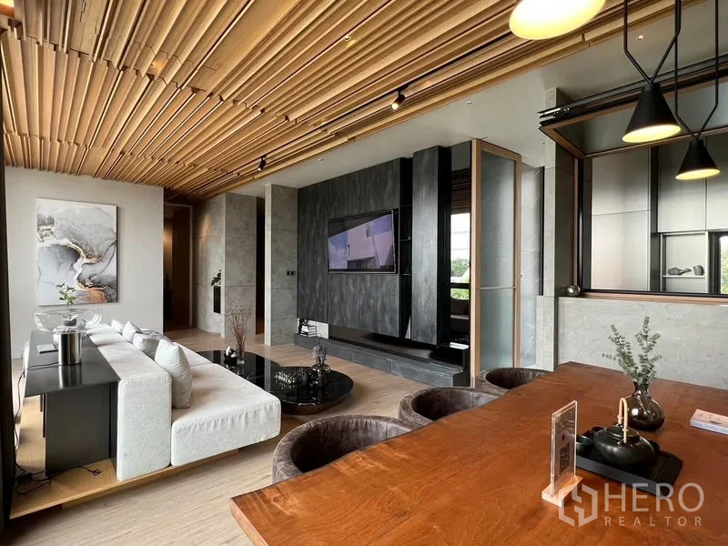 Home Office for sale in Prawet, Bangkok - Dining area and living room with pendant lighting and a built-in TV feature wall.