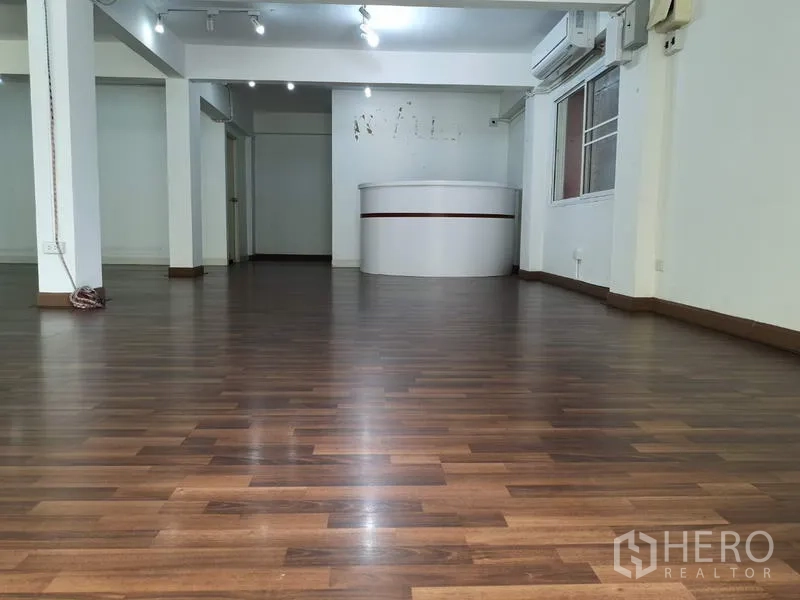 Office Space for rent in Khlong Toei, Bangkok - Open-plan office in Phra Khanong with wood flooring, track lights and a curved reception counter.