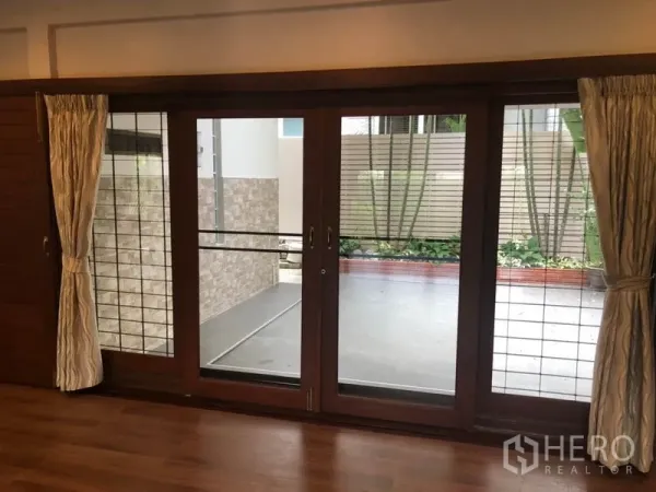 Detached House for rent in Watthana, Bangkok - Sliding glass doors with curtains leading to a private terrace and planters.