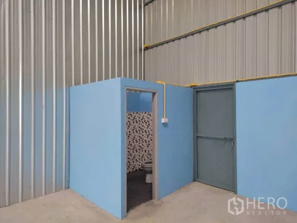 คลังสินค้า ให้เช่าในBang Yai, Nonthaburi - ห้องน้ำในตัวและประตูทางออกด้านข้างภายในโกดัง ผนังกั้นสีฟ้า กระเบื้องลาย