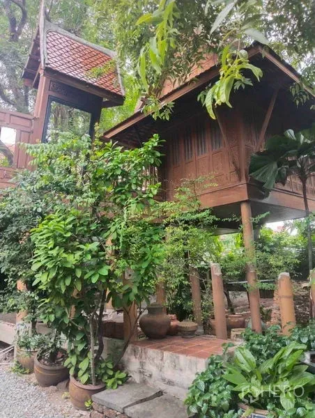 Detached House for rent or sale in Suan Luang, Bangkok - Traditional Thai-style wooden stilt house with gabled roof surrounded by lush tropical garden.
