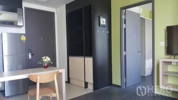 Condominium for rent in Watthana, Bangkok - Entry area with dark wood door, built-in shelving and storage, view toward bedroom and TV console.