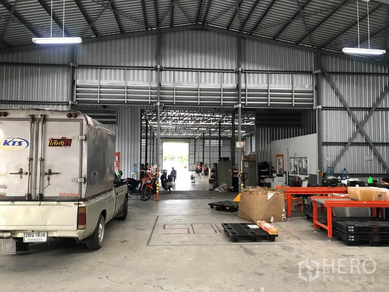 Warehouse for rent in Don Mueang, Bangkok - Central aisle of the warehouse showing workstations and rear loading dock doors.