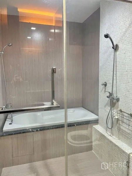 公寓 出租在Watthana, Bangkok - 浴室带玻璃淋浴间与坐凳，另设独立浴缸与手持花洒。