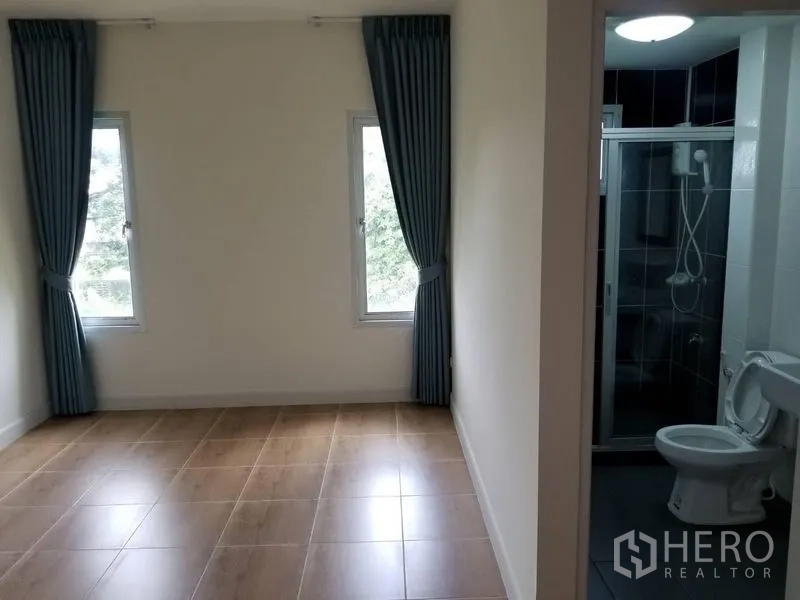 联排别墅 出租在Bang Kapi, Bangkok - 卧室与套内卫浴，双窗及蓝色窗帘