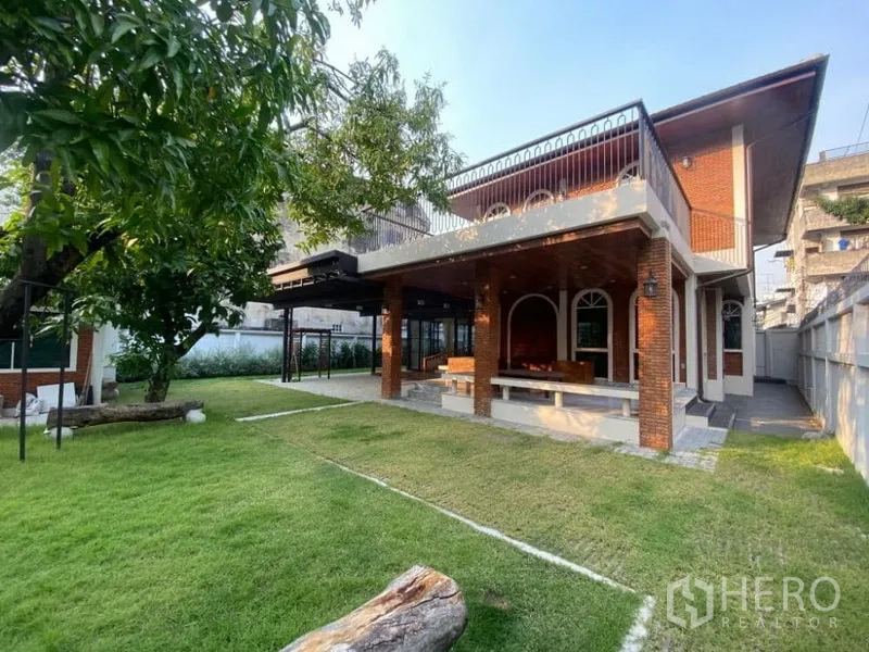 Detached House for rent in Ratchathewi, Bangkok - Two-storey brick detached house with arched veranda and a large green lawn with mature tree.