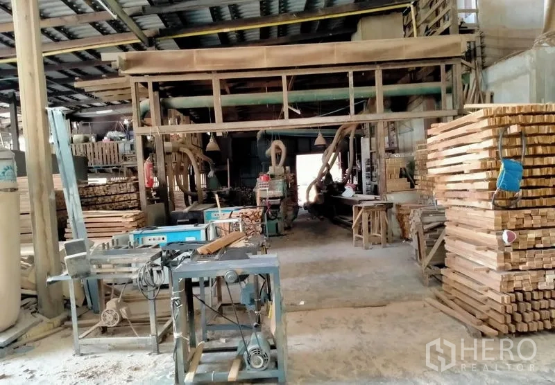 Warehouse for sale in Mueang Nonthaburi, Nonthaburi - Workshop interior showing industrial saws, conveyors and stacked boards.