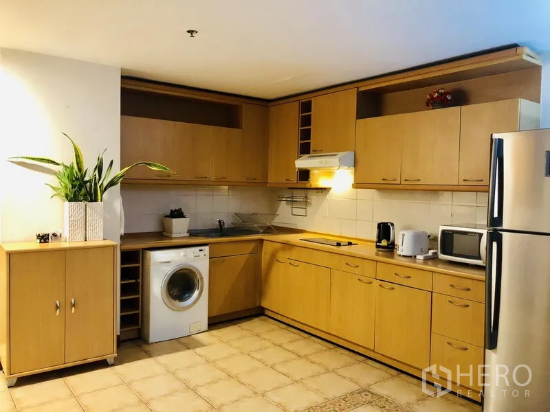 คอนโด ให้เช่าในPathum Wan, Bangkok - ครัวบิวท์อินไม้โทนอ่อนรูปตัวแอล ตู้เก็บของเยอะ พร้อมเครื่องซักผ้าและเครื่องใช้ไฟฟ้า