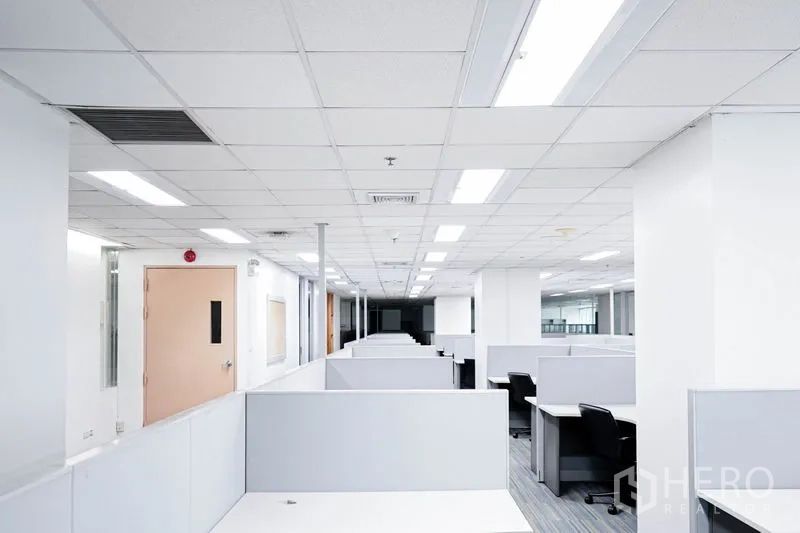 Office Space for rent in Watthana, Bangkok - Long corridor of workstations with partitions and a side door in a modern office.