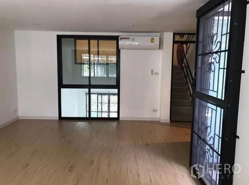 Townhouse for rent in Wang Thonglang, Bangkok - Second-floor family area with glass partition, air conditioner, and stair access.