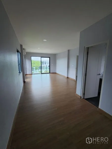 Detached House for rent in Bang Phli, Samut Prakan - Long upstairs family room with wood flooring and sliding doors to a balcony.