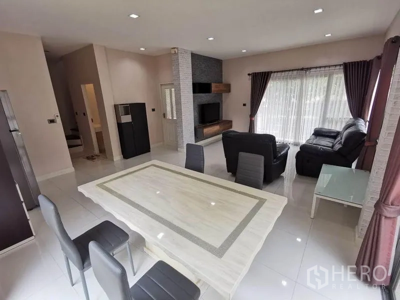 Detached House for rent in Prawet, Bangkok - Open-plan living and dining room with leather sofas, dining table and sliding glass doors.