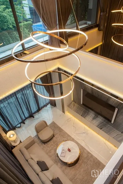 独立式住宅 出租或出售在Bangkok - 俯视双层挑高客厅与环形艺术吊灯。