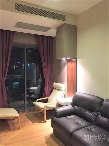 คอนโด ให้เช่าหรือขายในWatthana, Bangkok - ห้องนั่งเล่นพร้อมโซฟาหนัง เก้าอี้พักผ่อน และประตูกระจกสไลด์ออกระเบียง