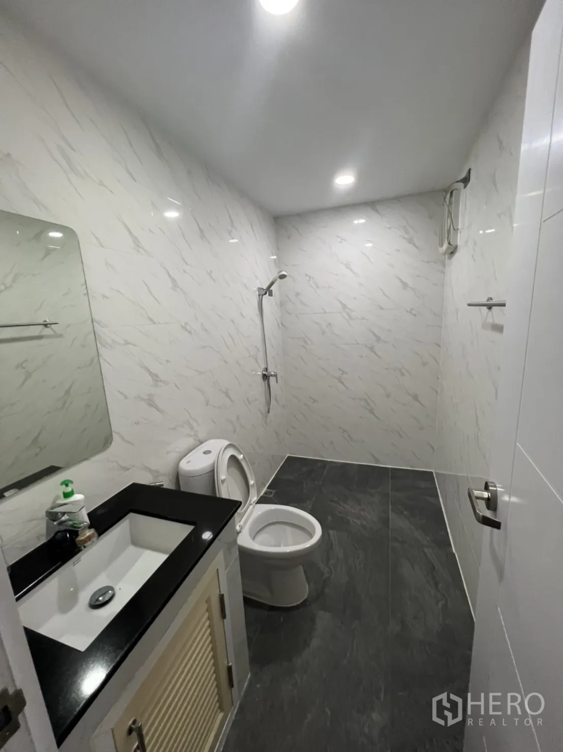Home Office for rent or sale in Phra Khanong, Bangkok - Second bathroom with marble-style walls, vanity, toilet and shower.