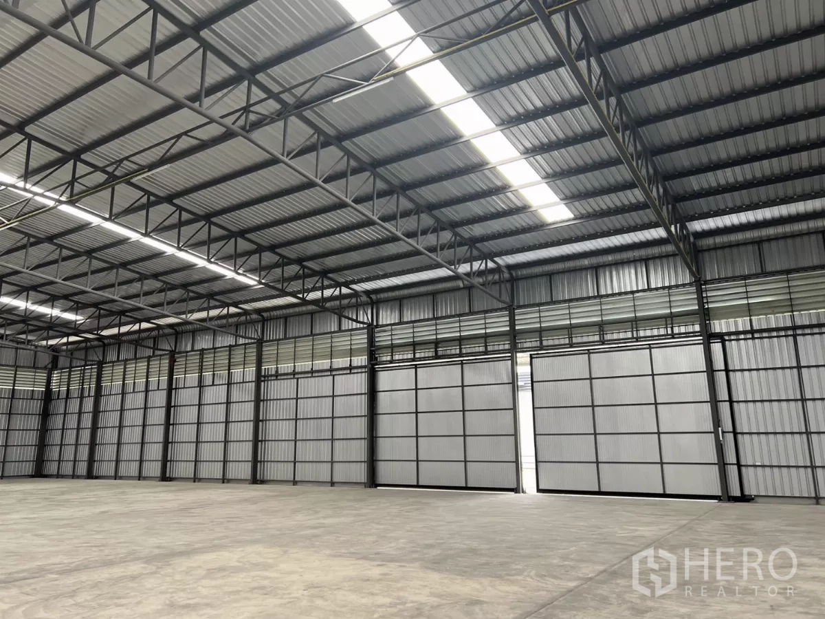 Warehouse for rent in Lat Lum Kaeo, Pathum Thani - Interior view with multiple sliding loading doors, steel beams, and skylights providing natural light.