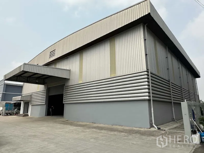 货栈 出租在Bang Phli, Samut Prakan - 金属板外墙仓库转角视角，带覆盖装卸口与卡车通道。