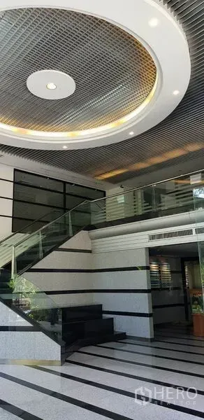 办公空间 出租在Khlong Toei, Bangkok - 现代大堂，设玻璃楼梯、条纹地面与环形吊顶。